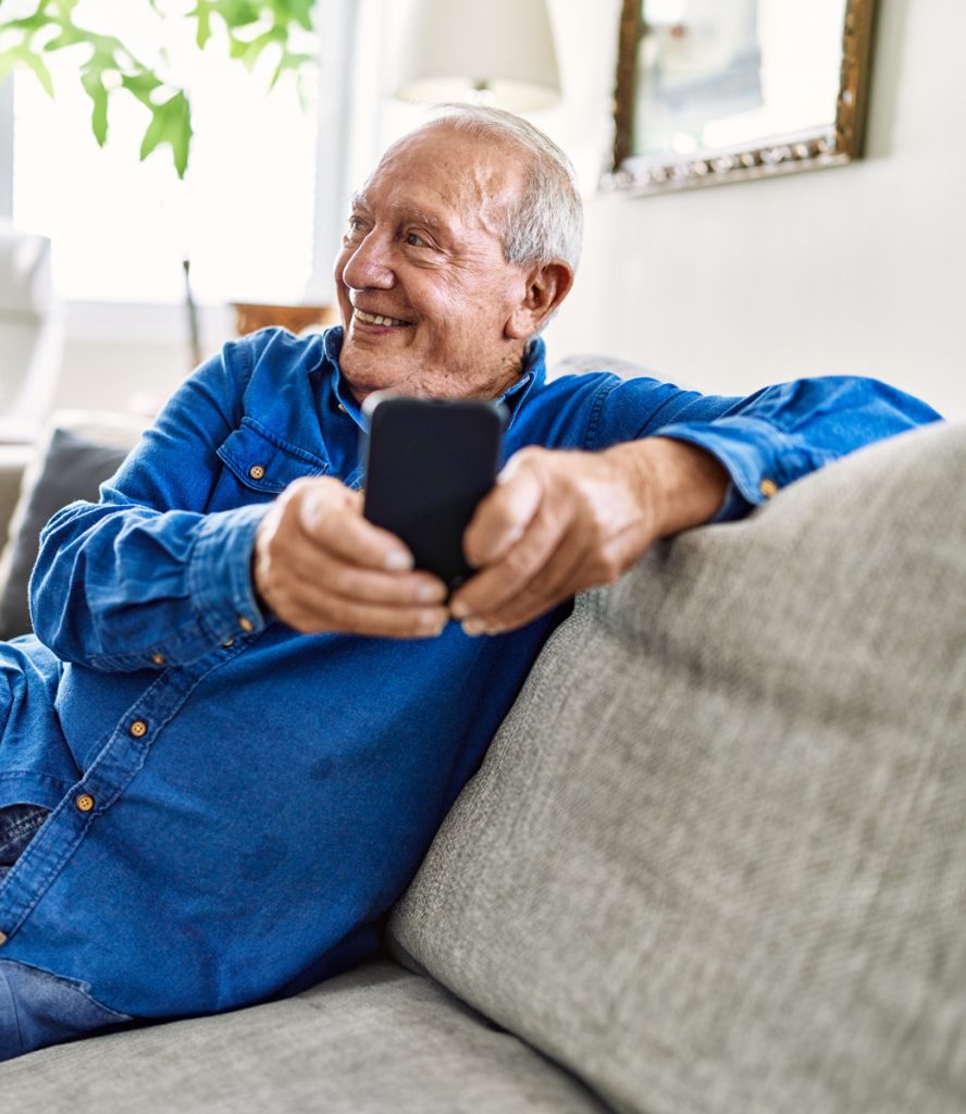 older man using his phone at his home